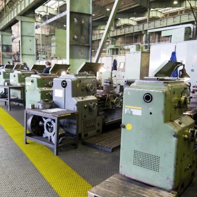 Row of green metal lathes in factory.